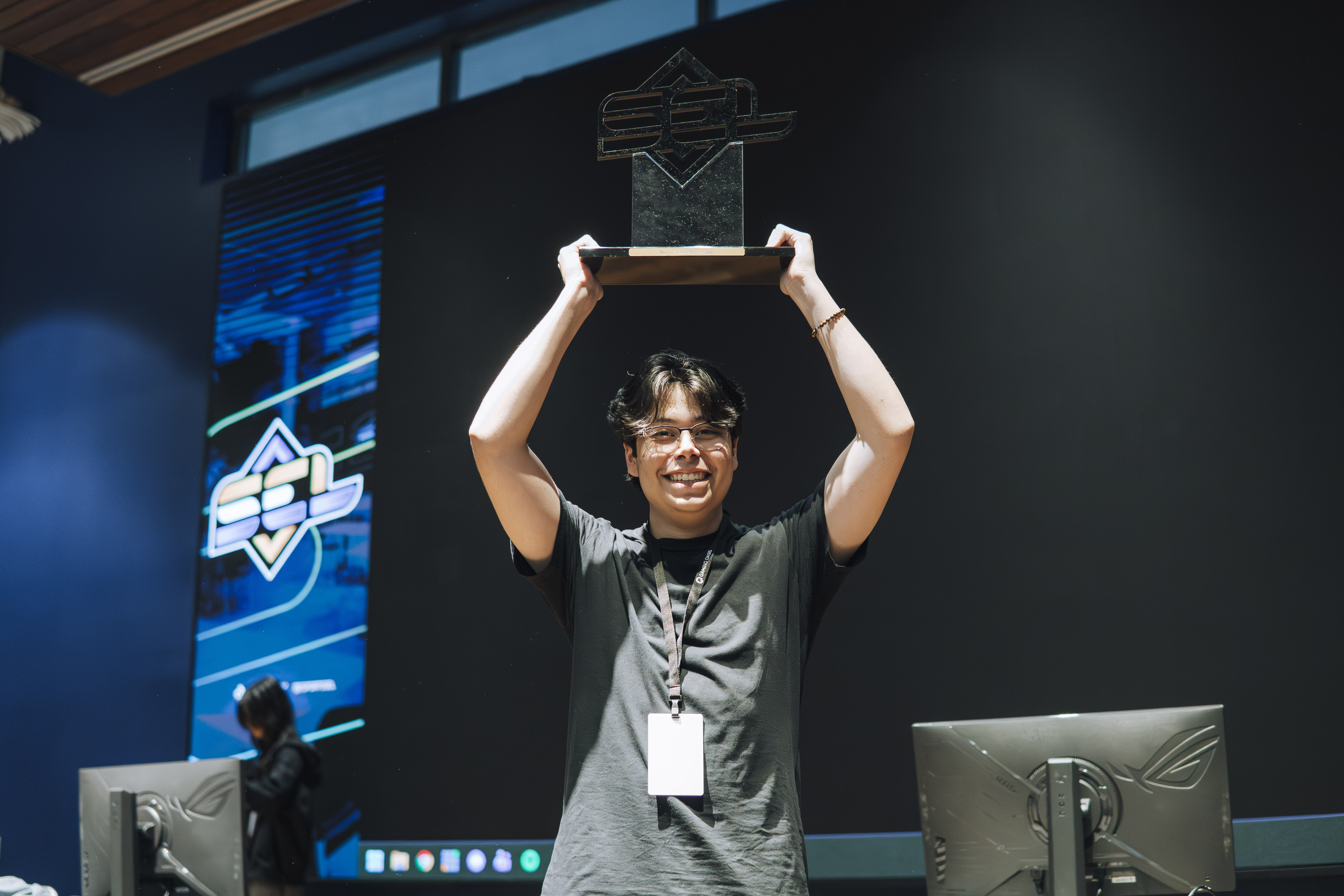 SEL competitor celebrates with a championship trophy on stage